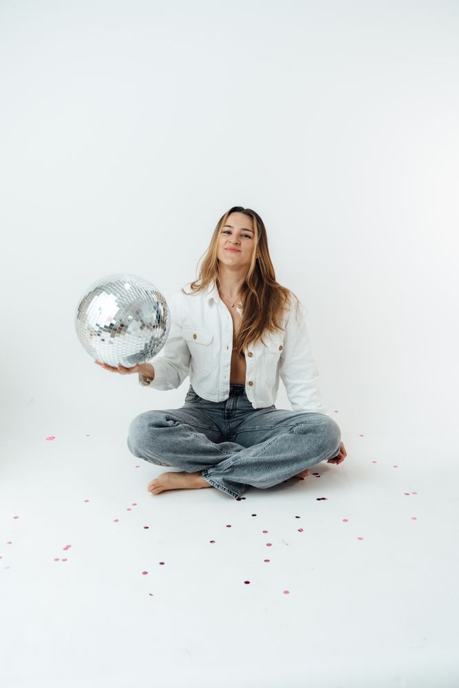The photographer sitting on the studio floor with a disco ball
