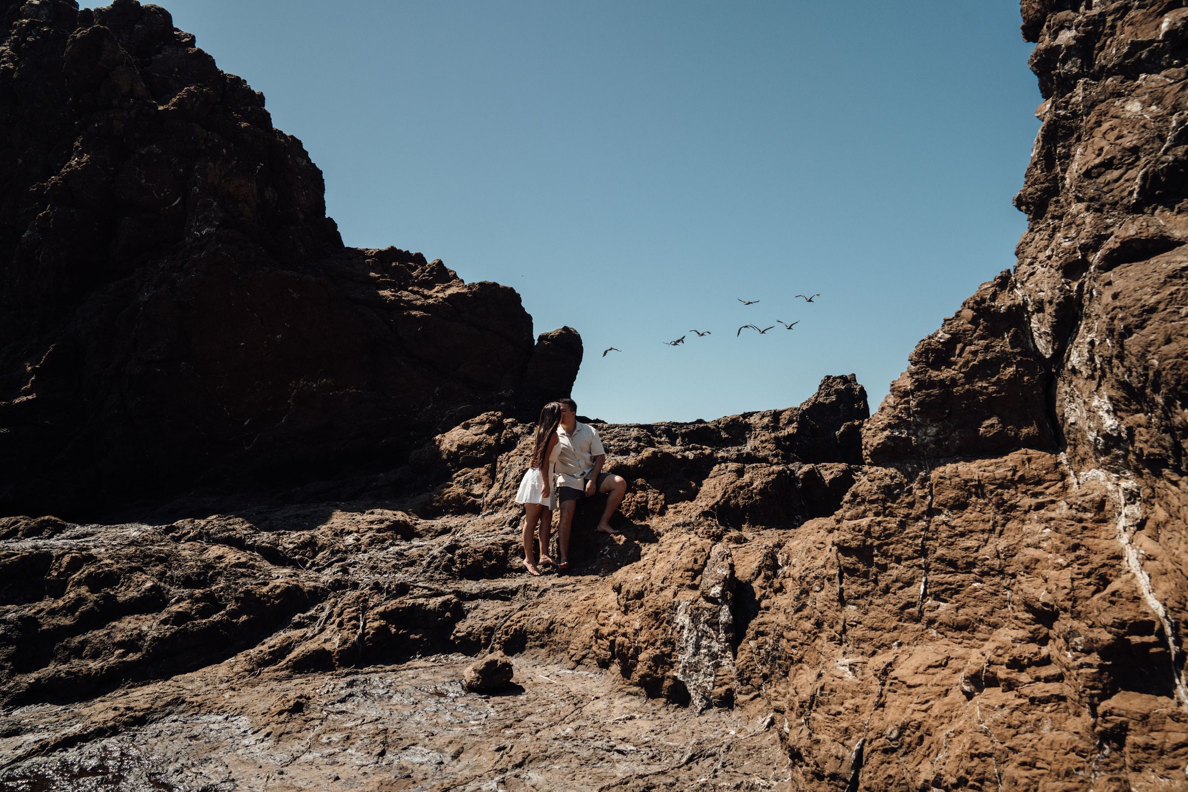 Couple standing between the rocks of a beach cove on the Pacific coast
