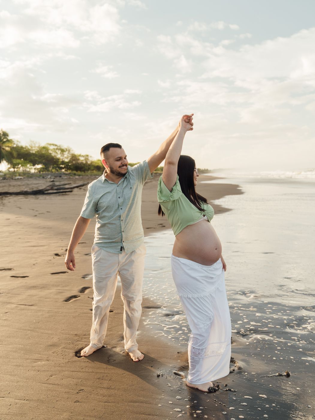 Couple dancing at the water’s edge, she is expecting