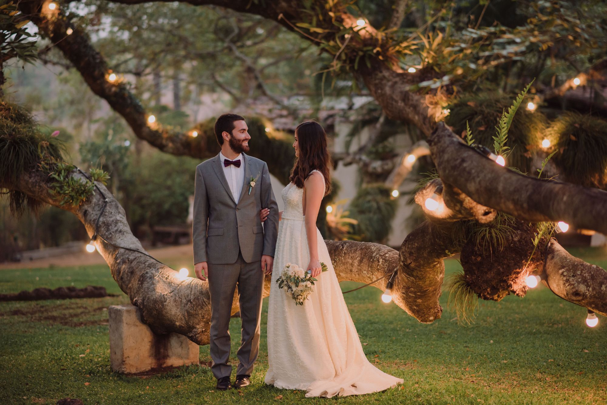 Bride and groom under a tree decorated with string lights