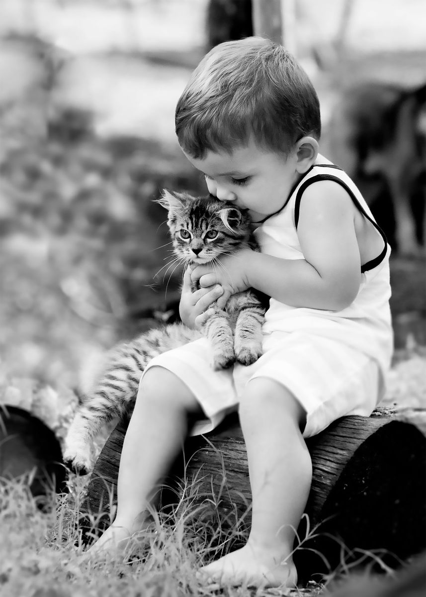 Black and white photo of a little boy hugging a kitten