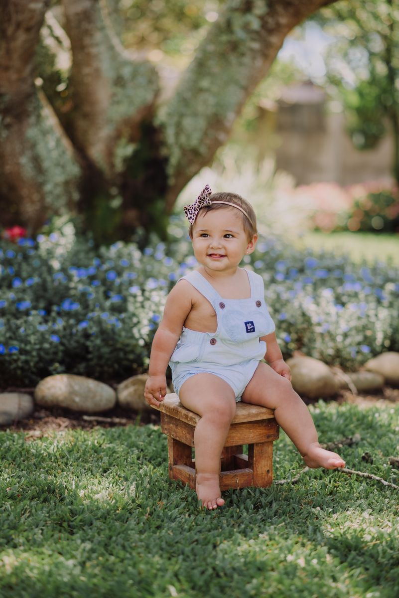 Baby girl sitting on a wooden stool in a garden