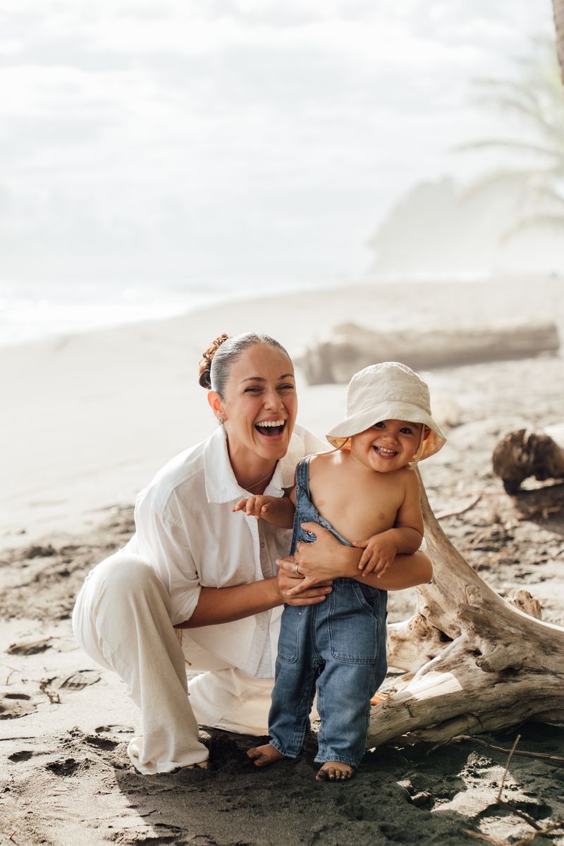 Mother laughing with her toddler on the sand